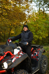 Obraz premium Man riding an ATV in autumn forest enjoying an off-road adventure. Concept of outdoor activity, freedom, thrill, and nature connection.