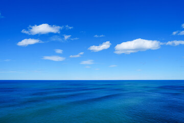 Fototapeta premium Bright blue ocean horizon with fluffy clouds