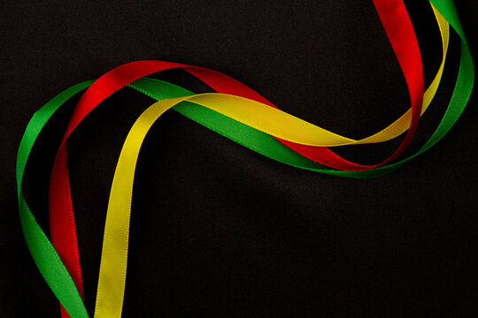 Black History Month, Juneteenth background. Red, yellow, green satin ribbons gently swirling on black silk background