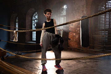 A woman in a boxing gym, portrait by the ropes, cinematic style, dark tones. Training and...