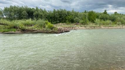 A serene spring landscape of the Bystrytsia Nadvirnianska river in Ukraine. A pebble riverbank and...