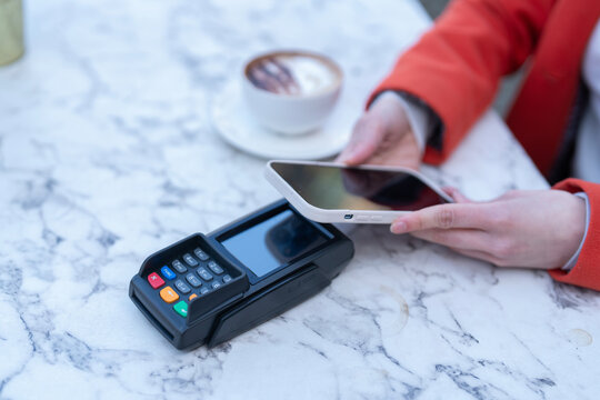 Mobile payment transaction at a cafe table during a relaxed afternoon with coffee and pastries - Powered by Adobe