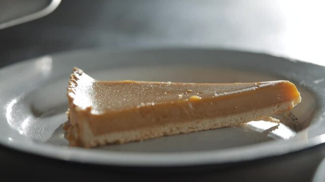 A slice of pie is on a white plate. The pie is cut in half and is sitting on a plate