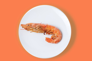 Red cooked shrimp on white plate isolated on a coral color background.