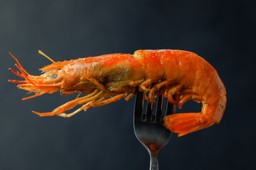 Fried shrimp on a fork isolated on black background. Close up.
