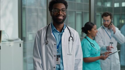 Joyful cheerful African American ethnic pediatrician therapist practitioner in glasses medical student with stethoscope doctor guy surgeon physician man male looking at camera inside clinic laboratory