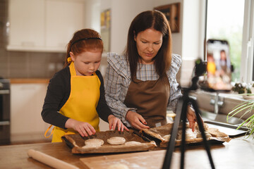 Mother and daughter baking together in a kitchen while preparing cookies in the afternoon, enjoying...