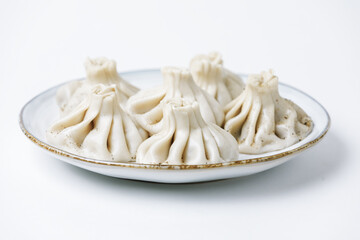 Plate with traditional georgian khinkali (dumplings) isolated on white background. Side view, copy space.