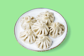 Plate with traditional georgian khinkali (dumplings) isolated on light green background. Flat lay, copy space.