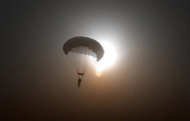 Silhouette of a paratrooper gracefully descending through the sky with an open canopy at sunset