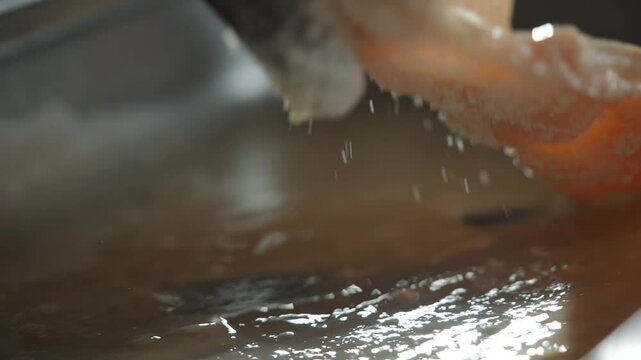 A person's arm is submerged in murky water, and they are reaching out to grab something. The water is splashing, and the person's arm is visible in the foreground