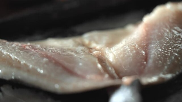 A close up of a piece of meat with a black glove on top of it. The meat is raw and has a slightly pinkish hue