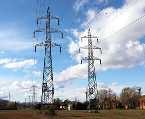 Power lines and transmission towers reaching across the rural landscape under a cloudy sky. Italy