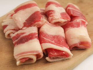 Sliced beef rolled on wooden cutting board