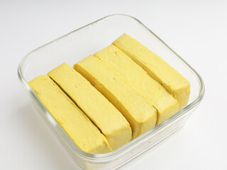 Yellow tofu, sliced, raw, on white background