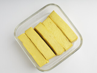Yellow tofu, sliced, raw, on white background