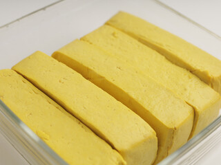 Yellow tofu, sliced, raw, on white background
