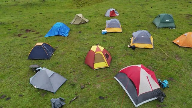 Colorful tents arranged on green grass during a sunny aerial pass over a mountain camp in the Ng&auml;be-Bugl&eacute; region