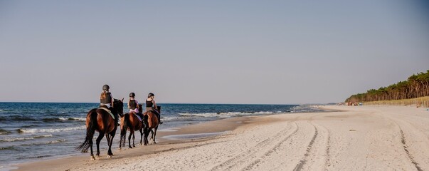 Wakacyjna letnia przygoda podczas obozu konnego dla dzieci i młodzieży podczas jazdy konnej w terenie. Grupowa wyprawa konno z instruktorem  na plażę nad morze w siodle.