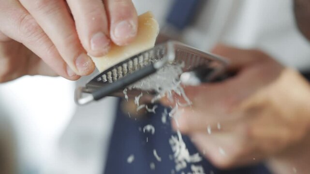 A person is using a cheese grater to grate cheese. The cheese is being grated into a bowl