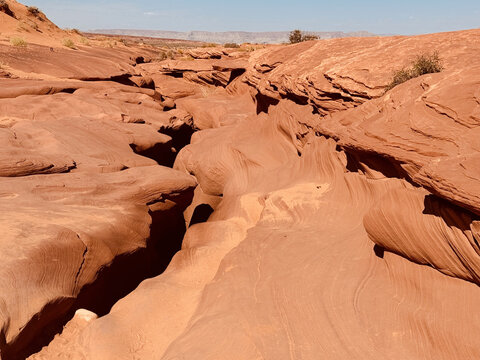 Beautiful view of a naturally carved red sandstone slot canyon featuring flowing, layered rock textures shaped by wind and water erosion. 