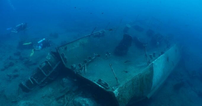 scuba divers exploring ship wreck underwater metal on sea floor