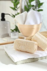 Different loofah sponges and towels on white table, closeup