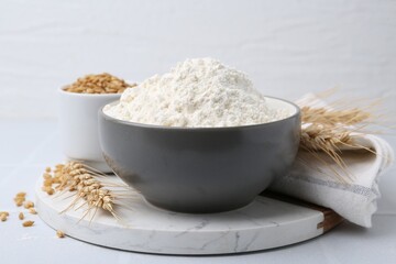 Wheat flour, grain and spikes on white table, closeup