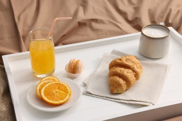 Tray with delicious breakfast on bed indoors, closeup