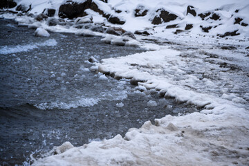 Cold waves crash against icy shoreline of a frozen lake during winter season