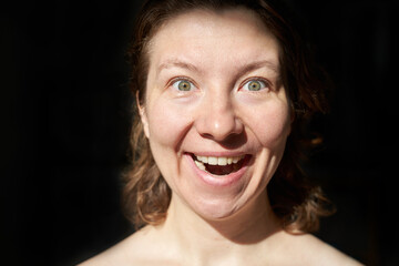 Joyful caucasian female adult with light eyes expressing happiness in close-up image.
