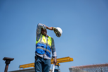 Tired Construction Worker Wiping Sweat Under the Hot Sun, Exhausted Engineer Taking a Break at...