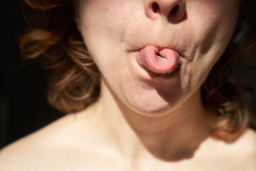 Young caucasian female demonstrating unique tongue rolling skill in close-up portrait. © elenavolf