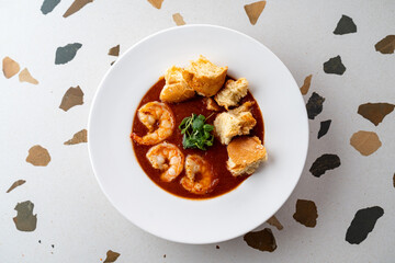 Delicious shrimp is cooked in a rich, spiced sauce and elegantly plated. Soft bread pieces complement this delightful culinary experience, perfect for sharing