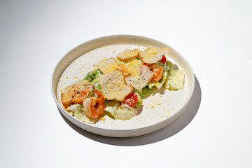 A vibrant seafood salad features succulent shrimp and fresh greens, complemented by crispy toppings. The dish is artfully arranged on a simple, elegant plate, embodying culinary creativity