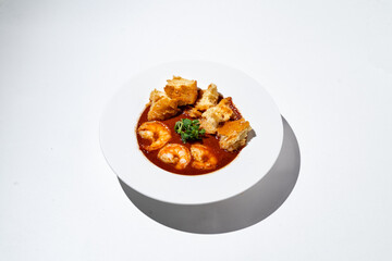 Bold flavors come together in this enticing shrimp stew accompanied by crunchy bread, beautifully displayed on a simple white plate. A culinary delight for seafood lovers