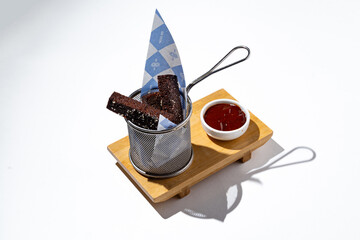 Elegant presentation features fresh chocolate sticks resting in a metal holder, accompanied by a small bowl of decadent sauce, all on a wooden tray that enhances the visual appeal