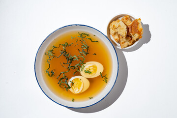 Experience a delightful combination of flavors with warm broth infused with herbs, accompanied by creamy soft boiled eggs and crunchy crackers. Perfect for a comforting meal