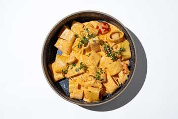A bowl filled with beautifully arranged creamy pasta featuring tender shapes and topped with vibrant herbs rests on a clean surface, inviting culinary delight and indulgence
