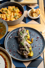 A beautifully plated dish features tender beef in a creamy sauce, surrounded by crispy potatoes, garnished artistically with microgreens. The inviting atmosphere enhances the dining experience