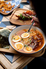 A steaming bowl of ramen filled with rich broth, tender noodles, and garnished with slices of egg and meat captivates diners. The inviting atmosphere enhances the culinary experience