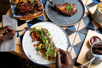 A person is savoring a carefully arranged plate filled with colorful salad, surrounded by appetizing dishes at a modern eatery, reflecting a vibrant culinary experience