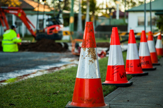 Reflective orange traffic cones in a row beside a work site