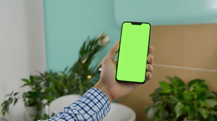 Hand Holding Smartphone with Green Screen in Indoor Office Environment
