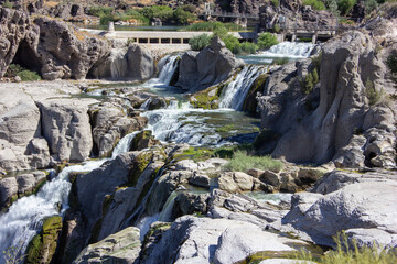 Waterfalls cascading over rocky terrain in a serene natural landscape during daylight hours
