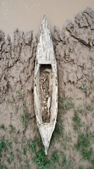 Aged wooden canoe stranded in mud.