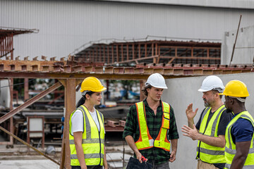 A group of civil engineers from different cultures and ethnicities exchange their ideas in a construction place or factory. People from diverse ethnic backgrounds engaging in meaningful discussions