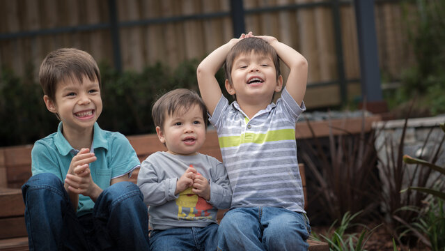 Naklejki Mixed race brothers play together in their suburban backyard