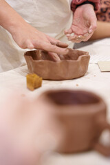 Hands working with wet clay to shape a handmade bowl during a pottery workshop