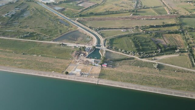 Dam wall and rural agricultural structures reservoir in Uzbekistan, top view